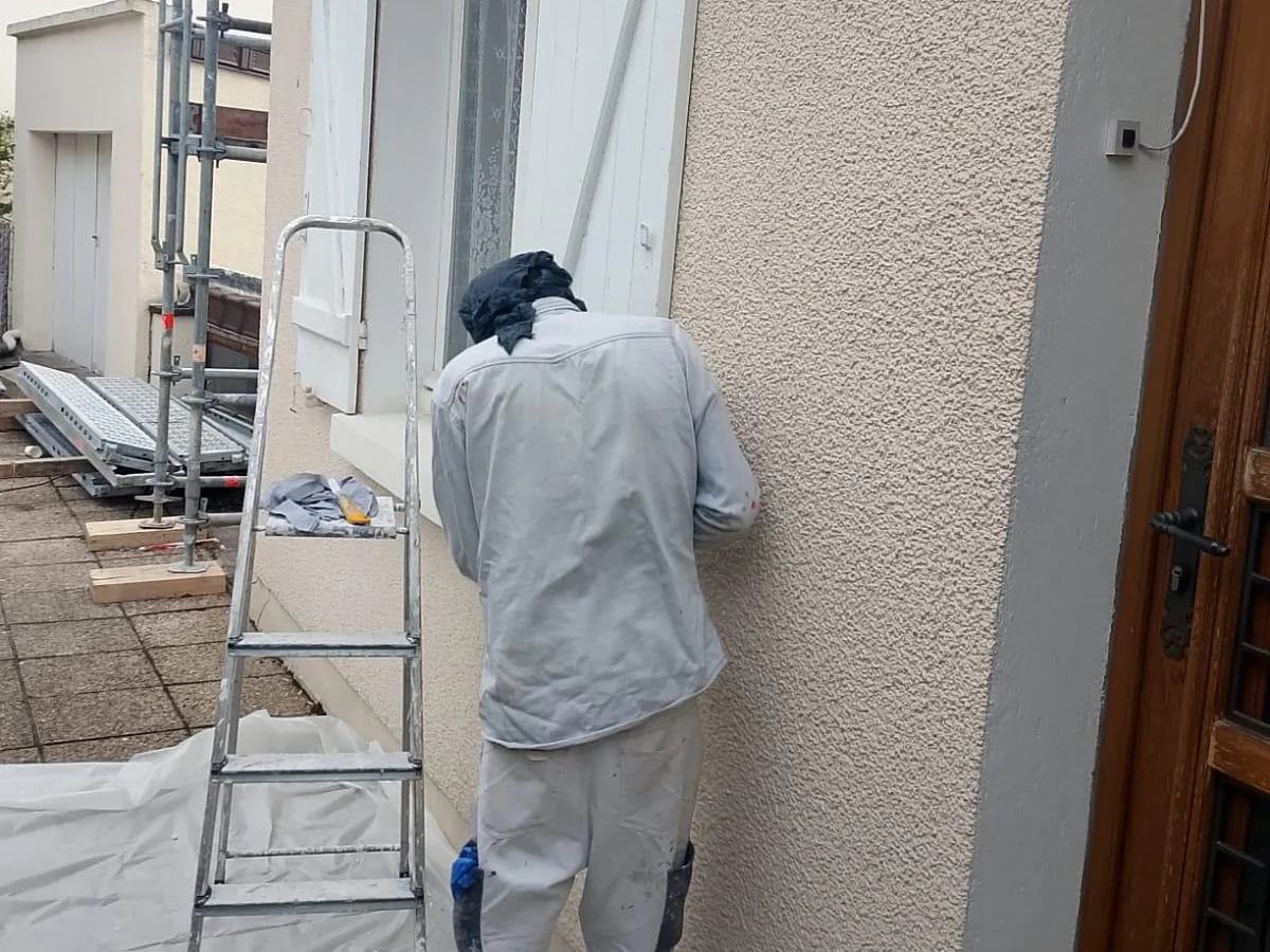 Professionnel appliquant un revêtement sur une façade pendant un chantier CDPF